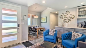 A modern living room with a sofa, armchairs, and a coffee table. There is a dining area with a table and chairs, and a kitchen with cabinets and a countertop. - Fort Collins Vacation Rental w/ Private Hot Tub! (Fort Collins)