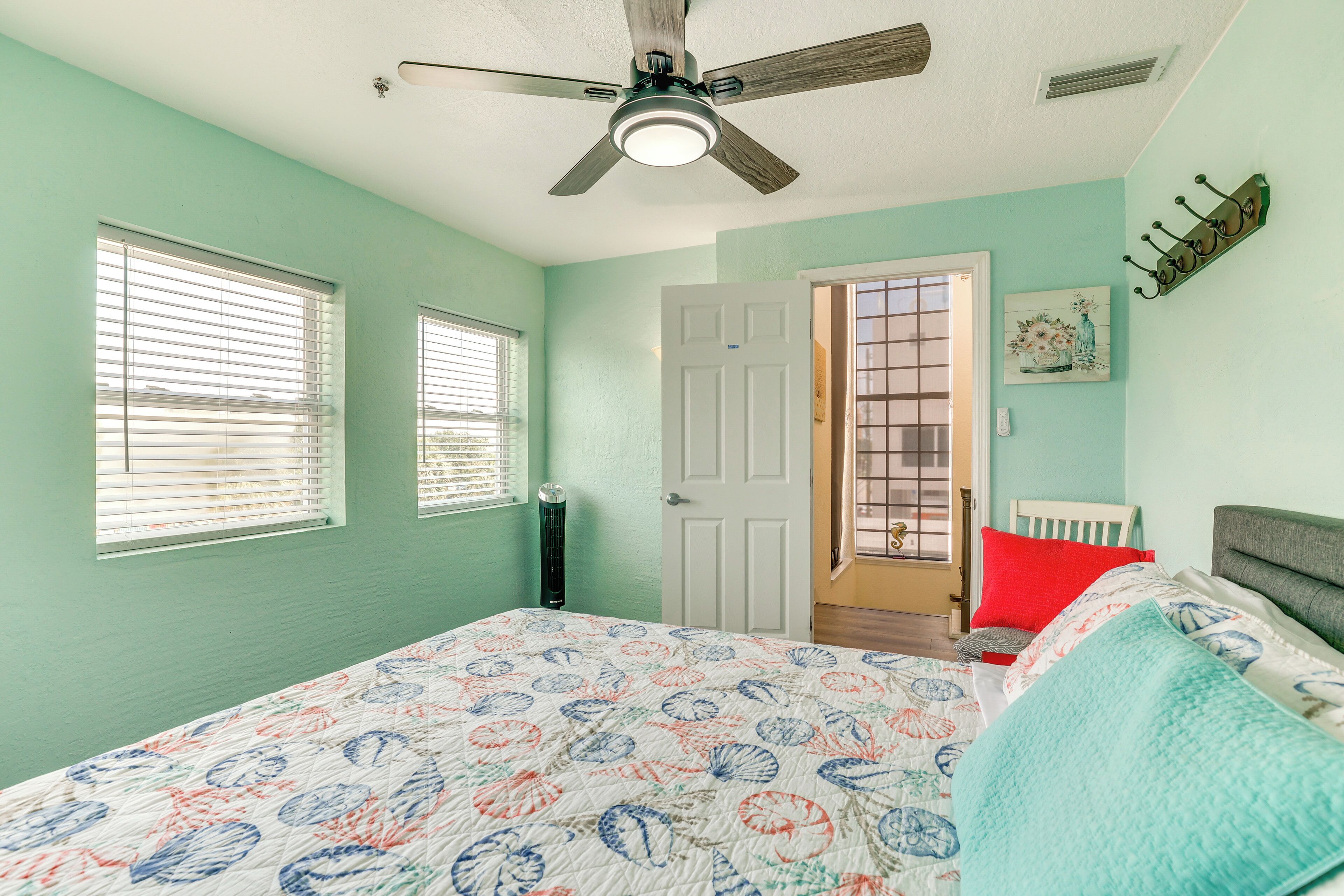 A bedroom with a bed, a ceiling fan, a door, and a window.