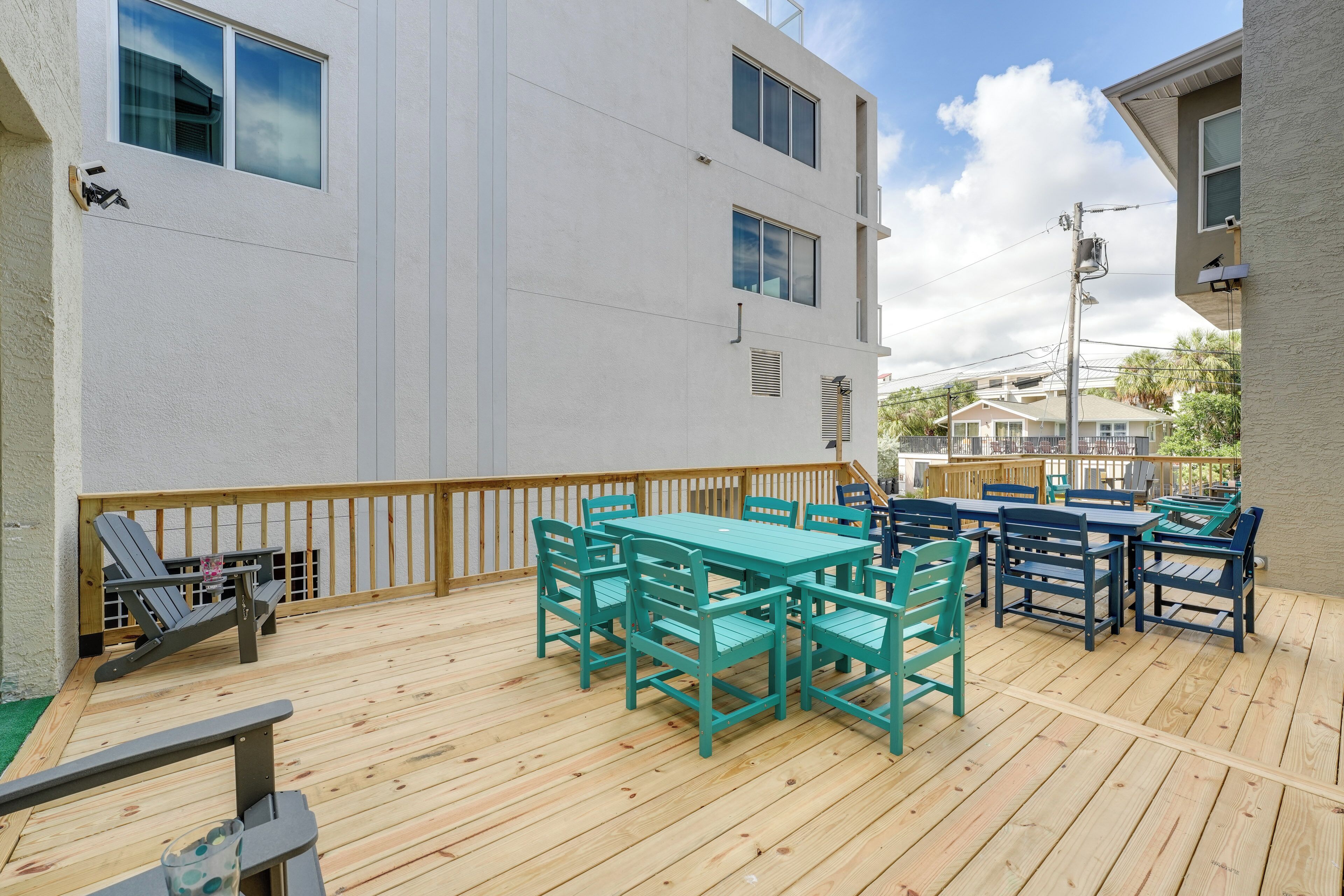 A deck with outdoor seating and a view of a white building.