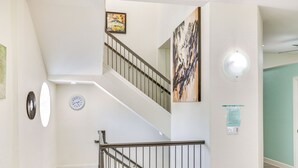 A staircase with a metal railing, a wall clock, and a painting. - Clearwater Beach Hideaway: Walkable Location! (Clearwater Beach)