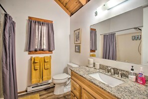 A bathroom with a white toilet, wooden vanity, granite countertop, and a large mirror. - Wintergreen Home w/ Deck - Near Skiing & Hiking! (Nellysford)