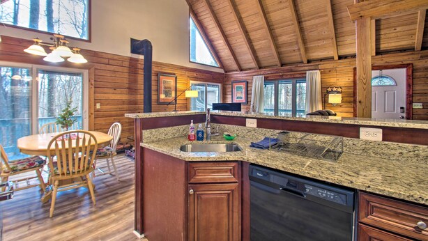 A spacious kitchen with granite countertops, wooden cabinets, and a large island with a dishwasher.