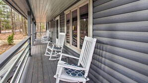 A covered porch with white rocking chairs and a wooden railing.