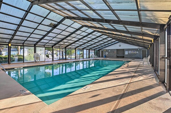 An indoor swimming pool with a glass ceiling, clear pool water, and a view of the outside. - Resort Home ~ 1 Mi to Myrtle Beach Access! (Murrells Inlet)