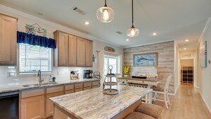 A modern kitchen with wooden cabinets, a marble island, pendant lighting, and a view of the dining area. - Resort Home ~ 1 Mi to Myrtle Beach Access! (Murrells Inlet)