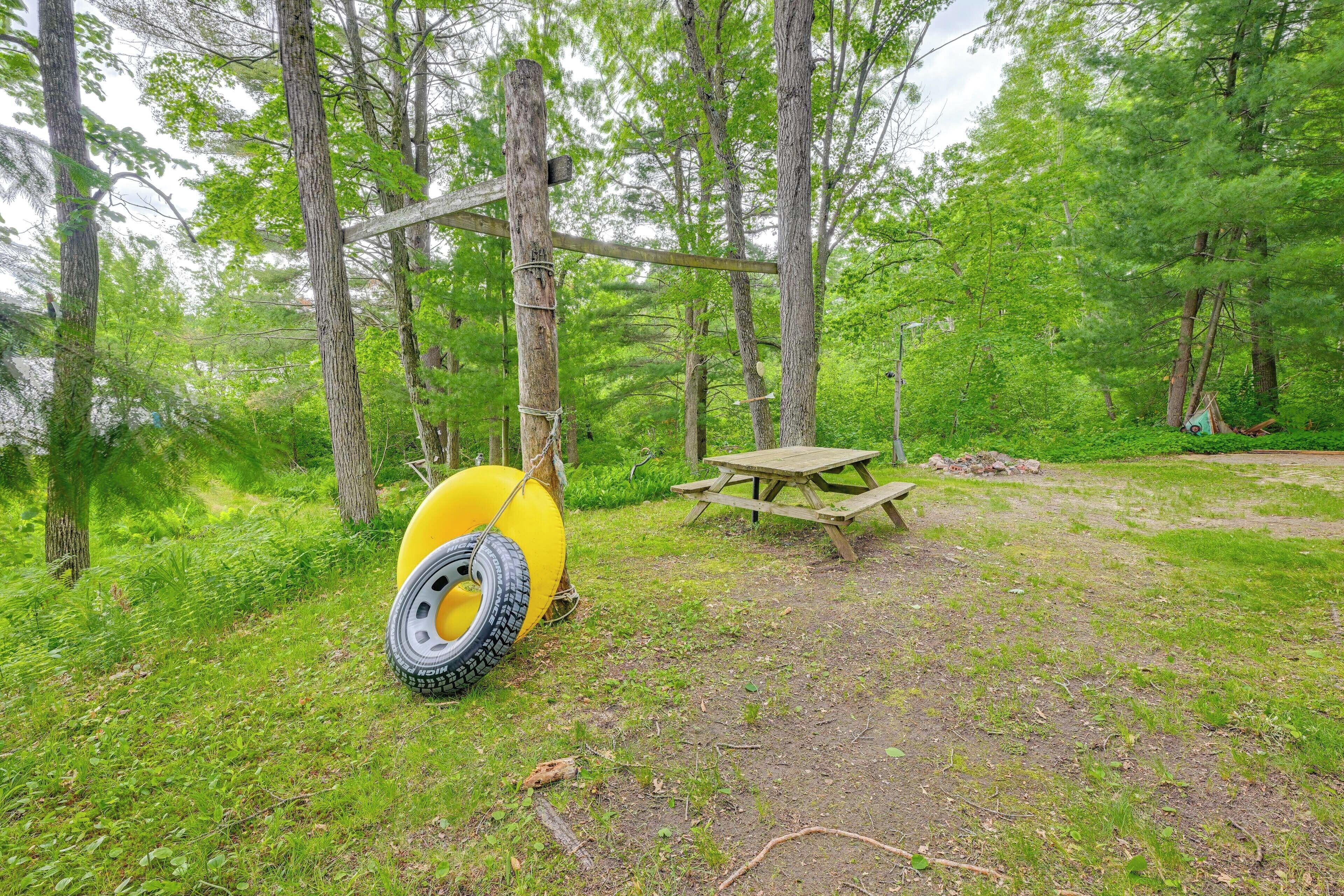 A picnic area with a wooden table and benches, surrounded by trees.