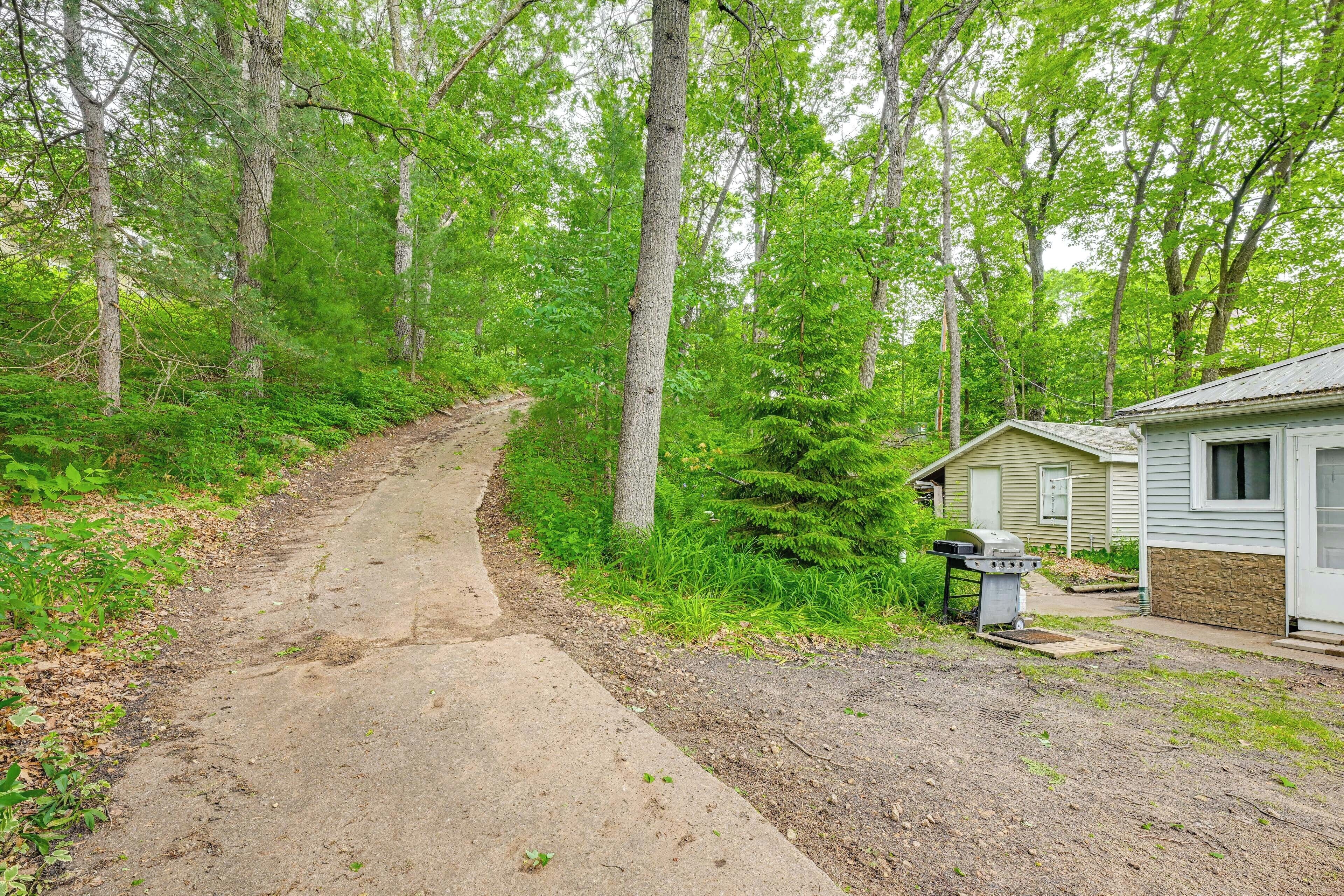 A concrete path leading to a small cabin with a grill outside.