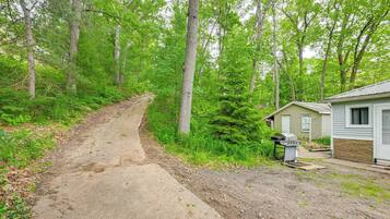 A concrete path leading to a small cabin with a grill outside.