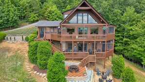 Une cabane en bois à plusieurs étages, dotée d’un balcon et entourée d’une végétation luxuriante.