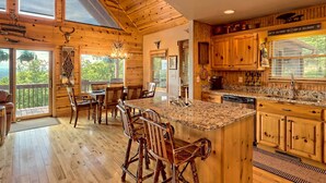 Une cuisine spacieuse dotée de meubles en bois, de plans de travail en granit et d’un grand îlot central avec des tabourets de bar.