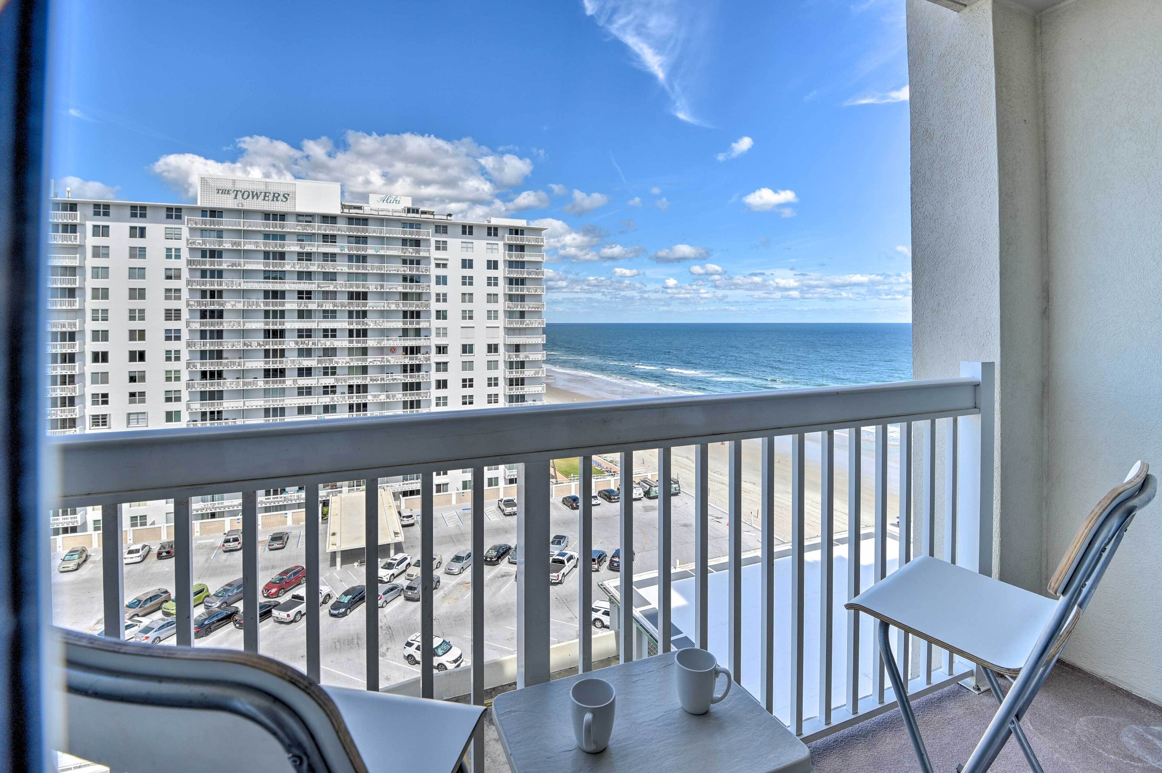 A balcony with a view of a parking lot and a hotel named "The Towers."