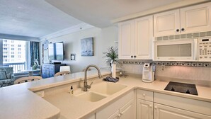 A modern kitchen with white cabinets, a built-in microwave, and a large sink.
