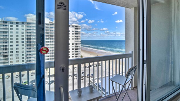 A balcony with a view of the beach and ocean, a no parking sign, and a "STOP UP" sign.