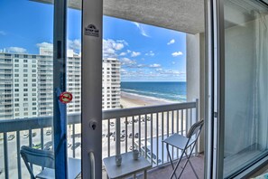 A balcony with a view of the beach and ocean, a no parking sign, and a "STOP UP" sign. - Vacation Vibe Condo: Eleventh-floor Ocean Views (Daytona Beach)