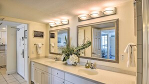 A modern bathroom with two sinks, large mirrors, and a decorative plant.