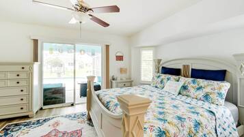 A bedroom with a bed, a dresser, a nightstand, a ceiling fan, and a view through a glass door.