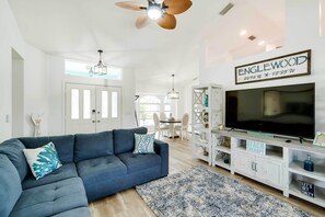 A modern living room with a sectional sofa, a large flat-screen TV, and a ceiling fan. - Family-friendly Englewood Getaway w/ Pool! (Englewood)