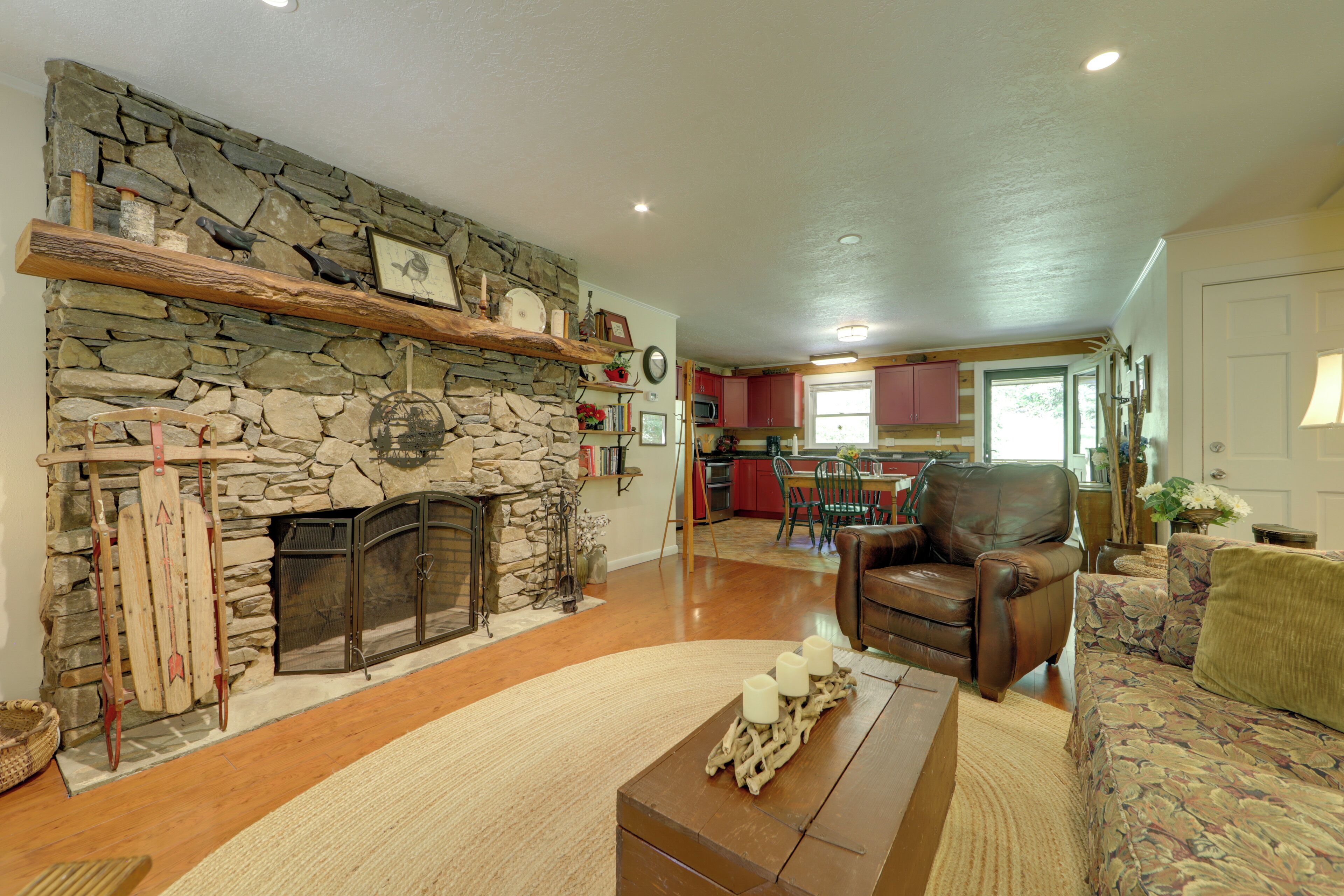 A living room with a stone fireplace, a leather armchair, and a sofa.