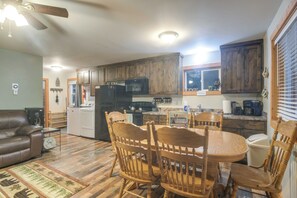A spacious kitchen with wooden cabinets, a dining table with chairs, and a ceiling fan. - Family Cabin - 25 Miles to Yellowstone Natl Park (Island Park)