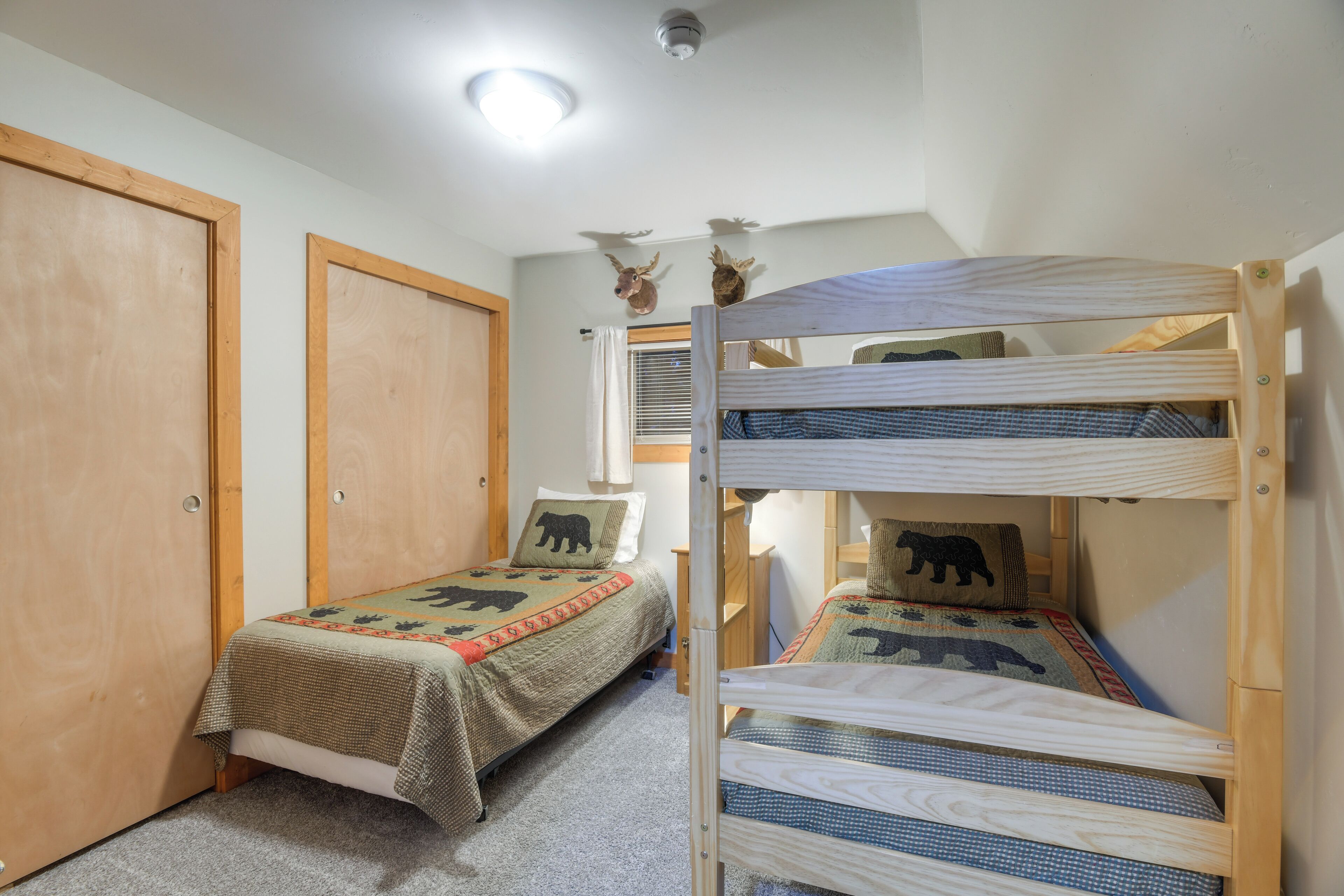 Une pièce avec deux lits superposés, une porte en bois et un luminaire au plafond.