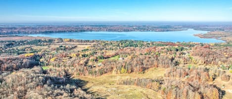 Vista panorâmica de uma paisagem à beira de um lago, com áreas arborizadas e céu azul límpido.