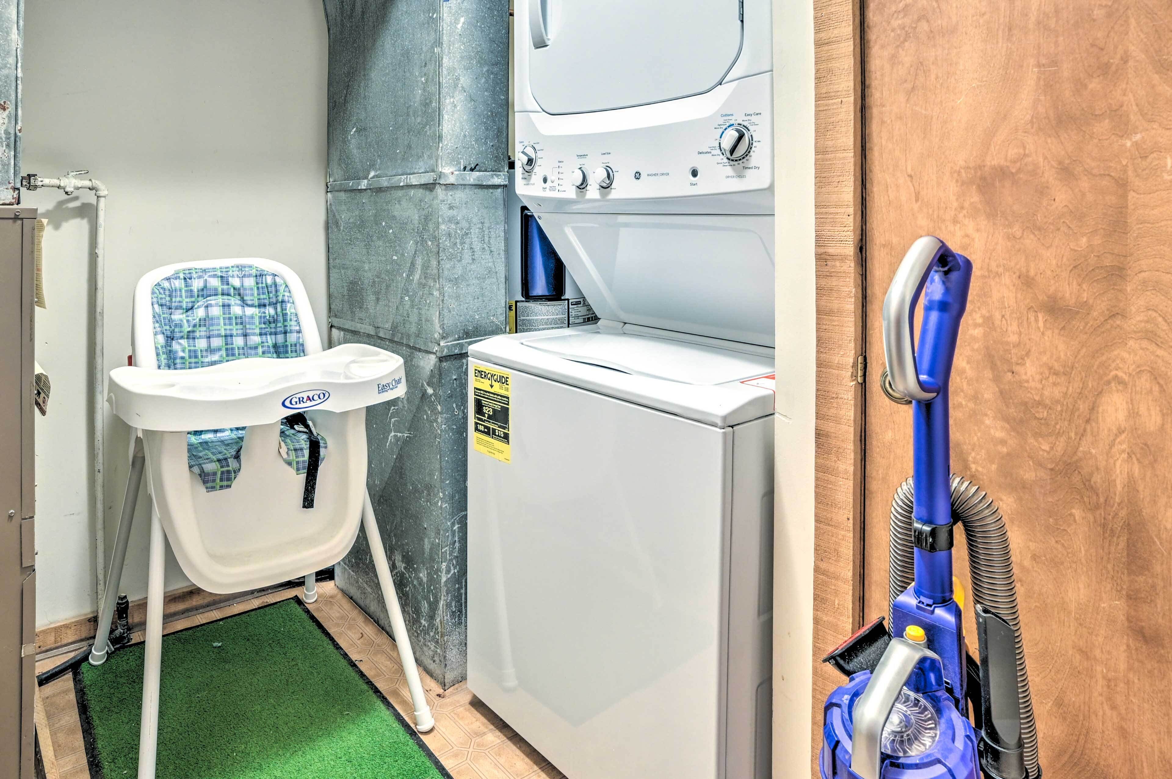 A laundry area with a washing machine, a dryer, a folding table, and a vacuum cleaner.