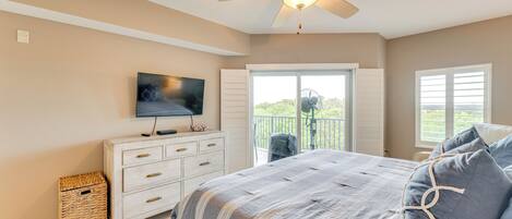 Une chambre avec un lit, un ventilateur de plafond, une télévision, une fenêtre et un balcon.
