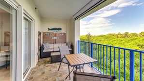 Ein Balkon mit Tisch und Stühlen, einem blauen Geländer und Blick auf Grünflächen.