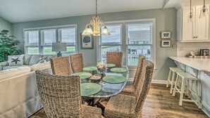 A dining area with a round table, wicker chairs, and a hanging light fixture. - Spacious Beach Cottage w/ Private Dock Access (Ocean Isle Beach)