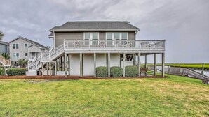 A two-story house with a balcony, a covered porch, and a view of the water. - Spacious Beach Cottage w/ Private Dock Access (Ocean Isle Beach)