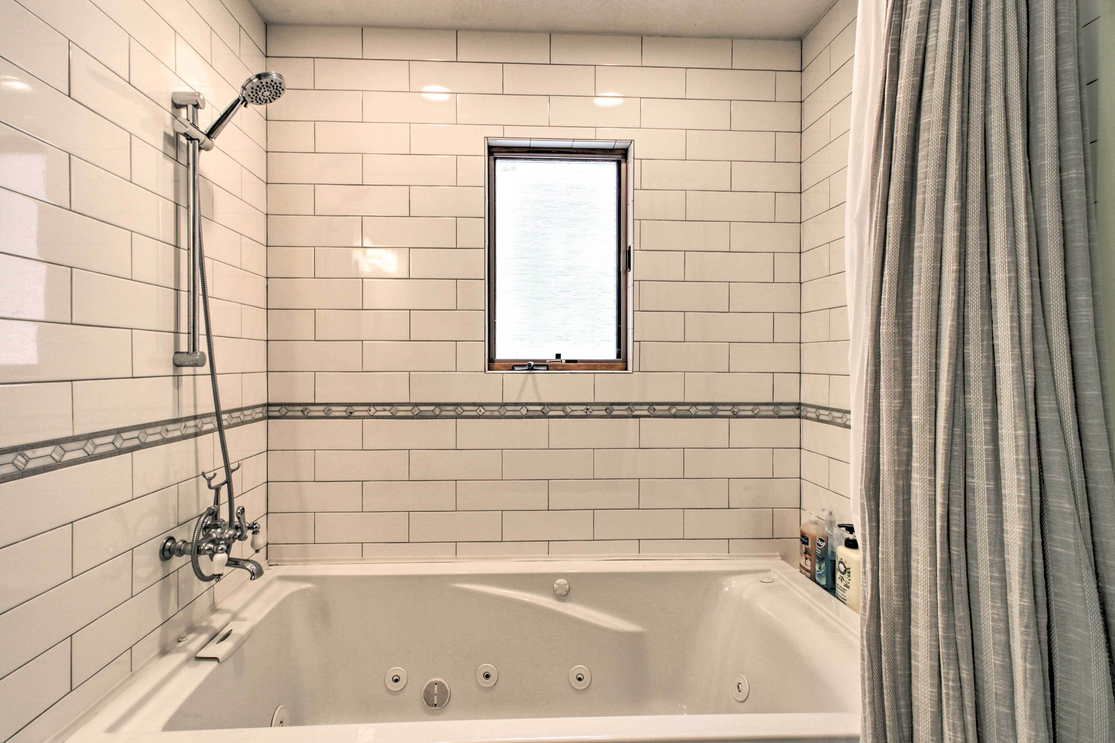 A bathroom with a bathtub, a shower, and a window.