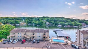 A hotel with a parking lot, a swimming pool, and a view of a river with boats.