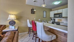 A compact kitchen with a microwave, stove, and bar stools.