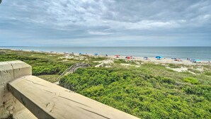 A beach with tents and umbrellas, a sandy shore, and a grassy area. - Beachfront Condo w/ Unobstructed Ocean Views! (Oak Island)