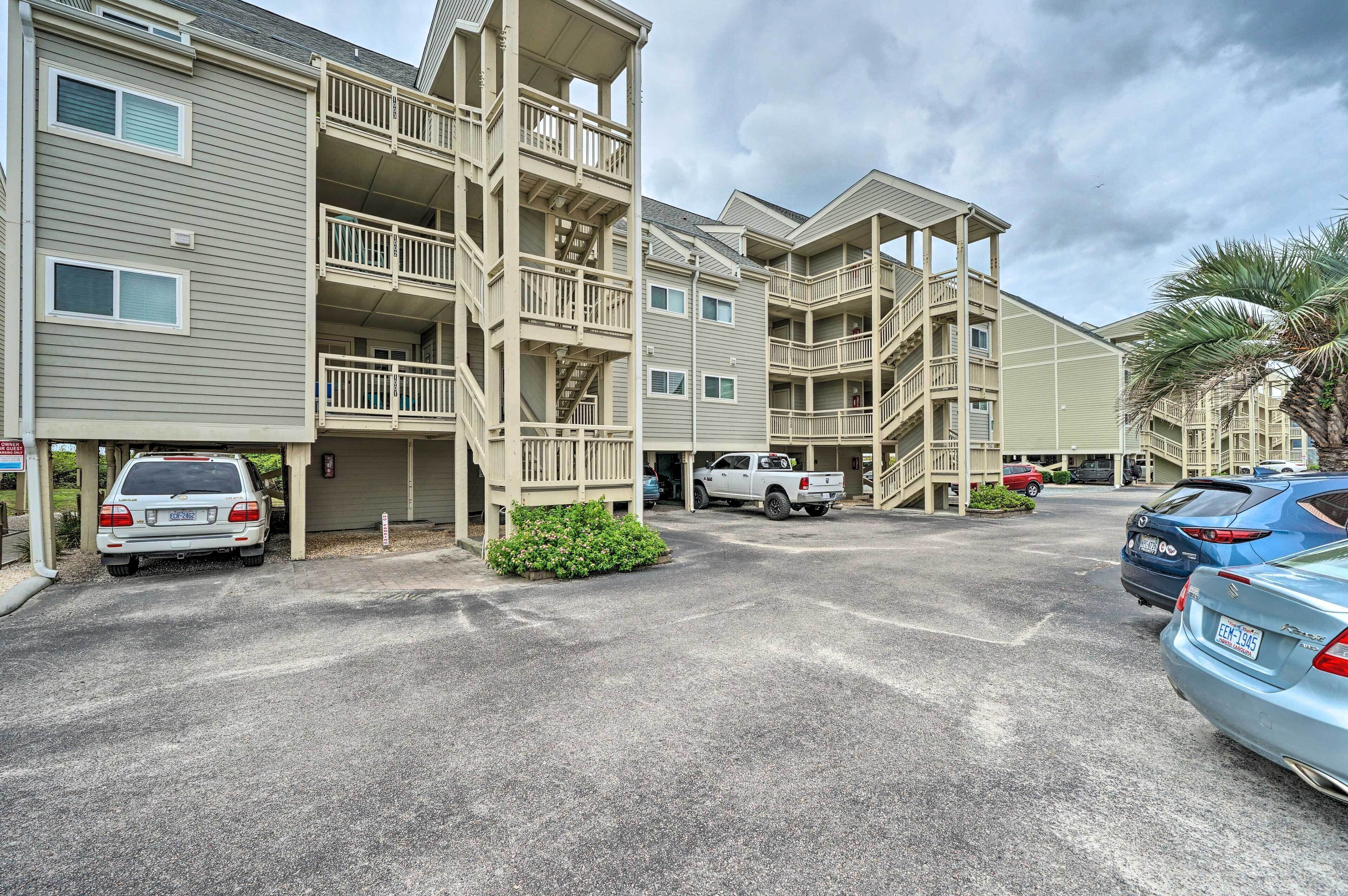 A multi-story residential building with balconies and a parking area.