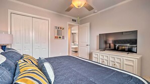 A bedroom with a large bed, a television, and a ceiling fan. - Beachfront Condo w/ Unobstructed Ocean Views! (Oak Island)