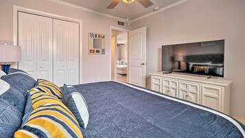A bedroom with a large bed, a television, and a ceiling fan.