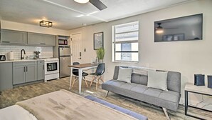A modern kitchen with grey cabinets, a dining table, and a grey sofa. - Pet-friendly Madeira Beach Studio Near Coast! (Madeira Beach)