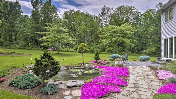 A garden with a stone pathway, a pond, and various shrubs and flowers. - Charming Lewiston Apt: 10 Miles to Niagara Falls! (Lewiston)