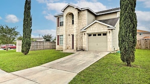 A two-story house with a stone facade, a garage, and a front yard with two tall trees. - Spacious Family Home Near San Antonio Hotspots! (San Antonio)