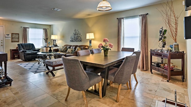 A dining area with a large table, four chairs, and a chandelier. There is a sofa and a coffee table in the background. - Spacious Family Home Near San Antonio Hotspots! (San Antonio)