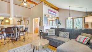 A spacious living area with a gray sofa, a round coffee table, and a dining table with chairs. - Home w/ Hot Tub: 5 Mi to Angel Fire Bike Park (Angel Fire)