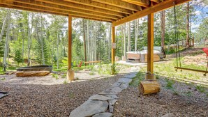 A covered outdoor area with a stone pathway, wooden beams, and a seating area with a grill and fire pit. - Home w/ Hot Tub: 5 Mi to Angel Fire Bike Park (Angel Fire)