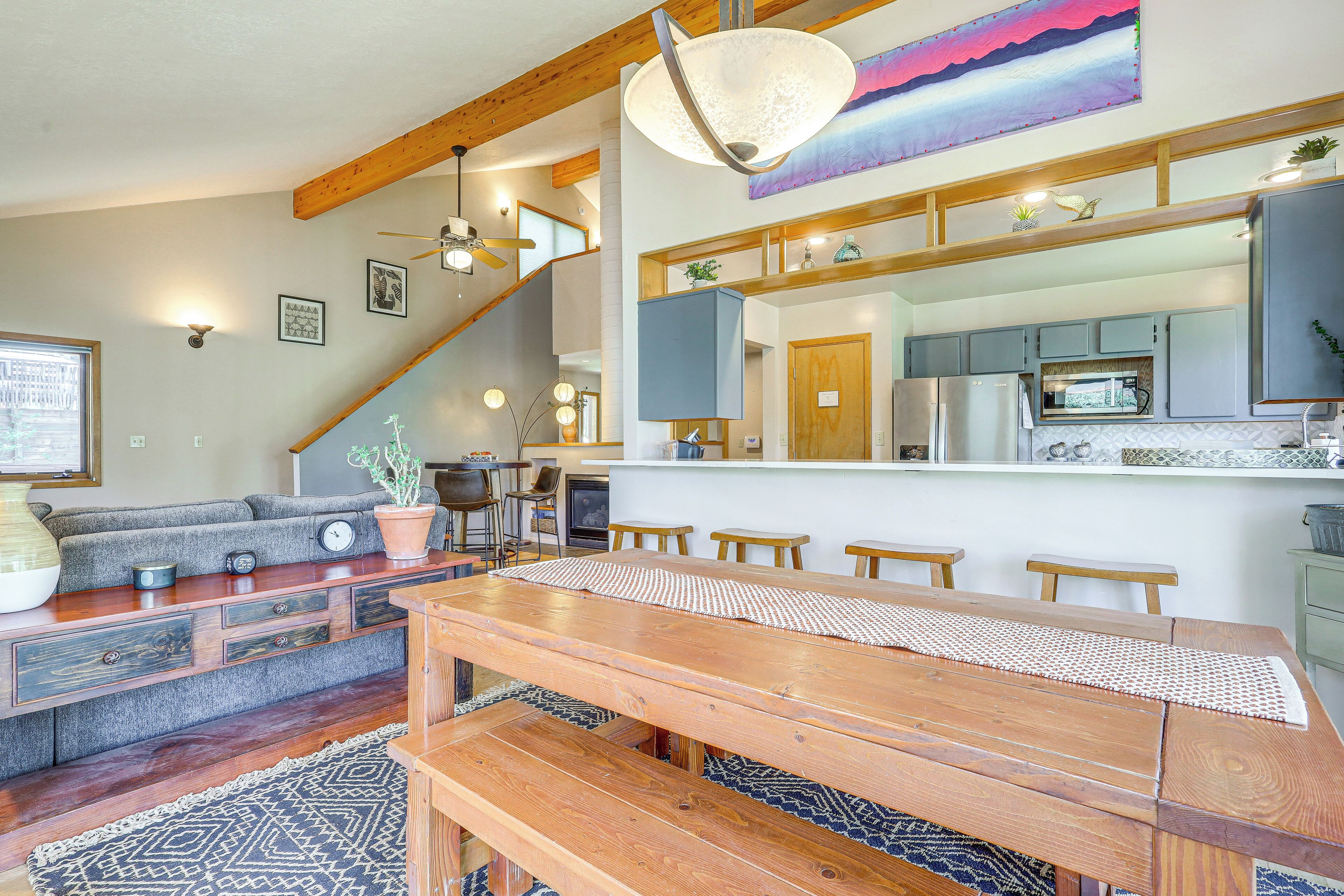 A spacious living area with a wooden dining table, a sofa, and a staircase leading to an upper level.