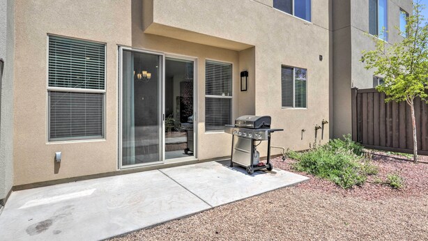 A modern building with a patio area featuring a grill and sliding glass doors. - Luxury Downtown Moab Townhome w/ Pool Access! (Moab)