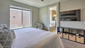 Une chambre dotée d’un grand lit, d’un ventilateur de plafond, d’un téléviseur fixé au mur et d’une porte coulissante donnant accès à une salle de bain.