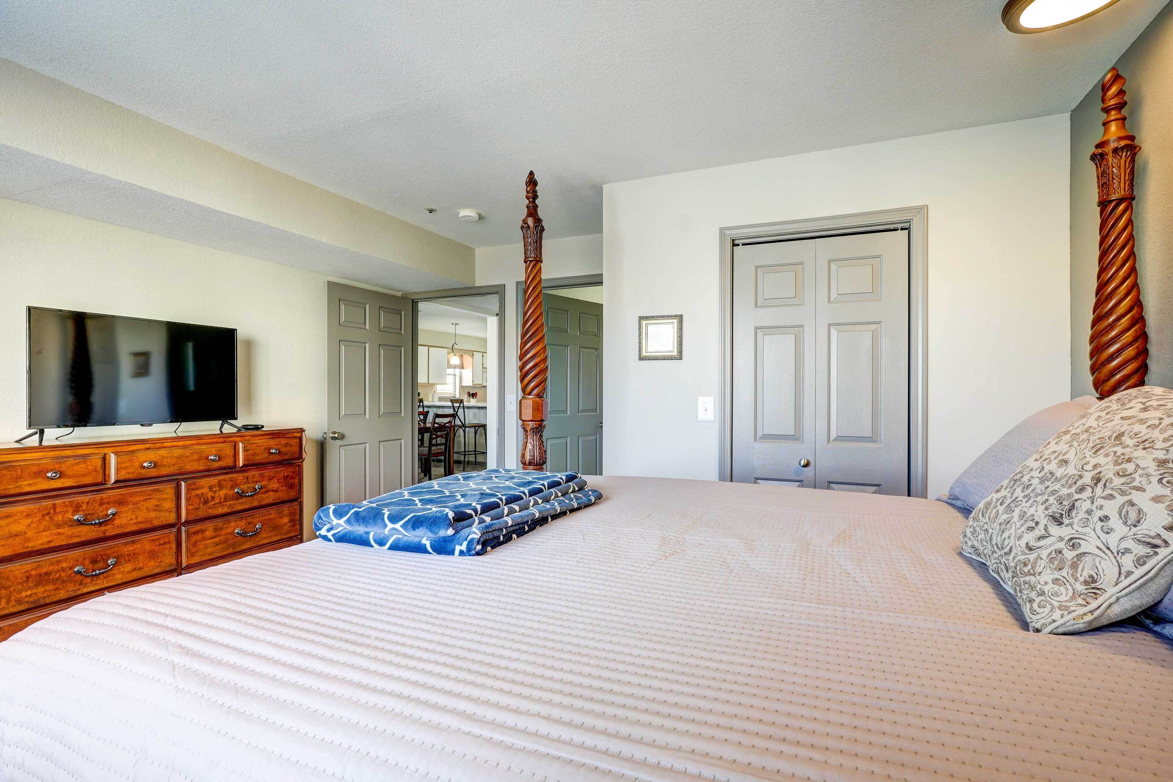 A bedroom with a large bed, wooden dresser, and a television on a stand.