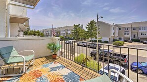 Un balcón con vistas a una calle residencial, una planta en maceta y una silla.