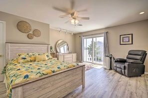 A bedroom with a bed, a ceiling fan, a chair, a window, and a door. - Brigantine Retreat w/ Balconies - Walk to Beach! (Brigantine)