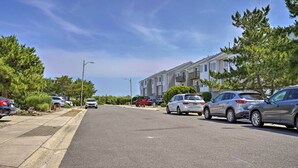 Una calle residencial con coches estacionados, una hilera de casas adosadas y cielo despejado.